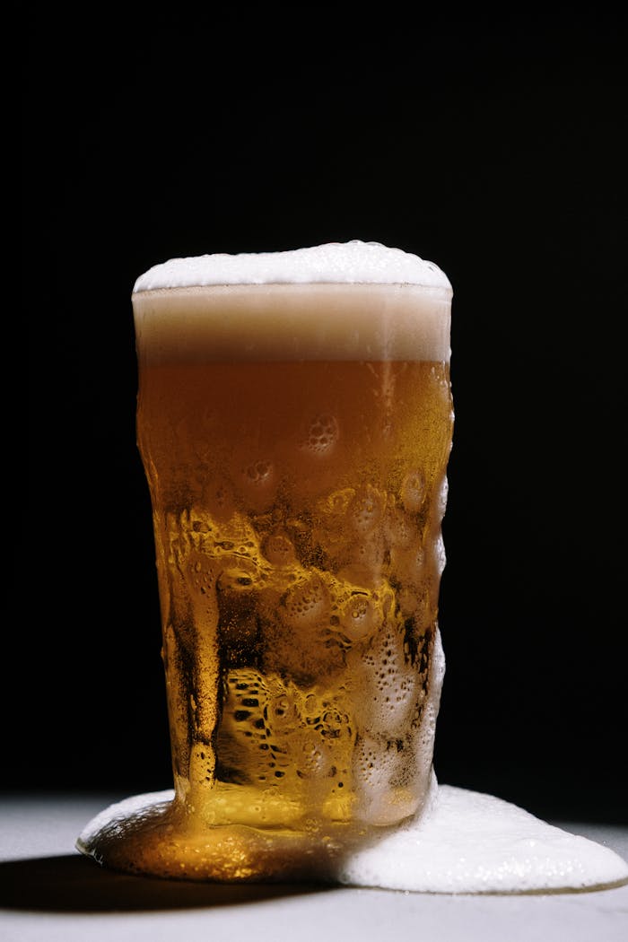 Close-up of a beer glass with foam on a dark background, emphasizing refreshment.