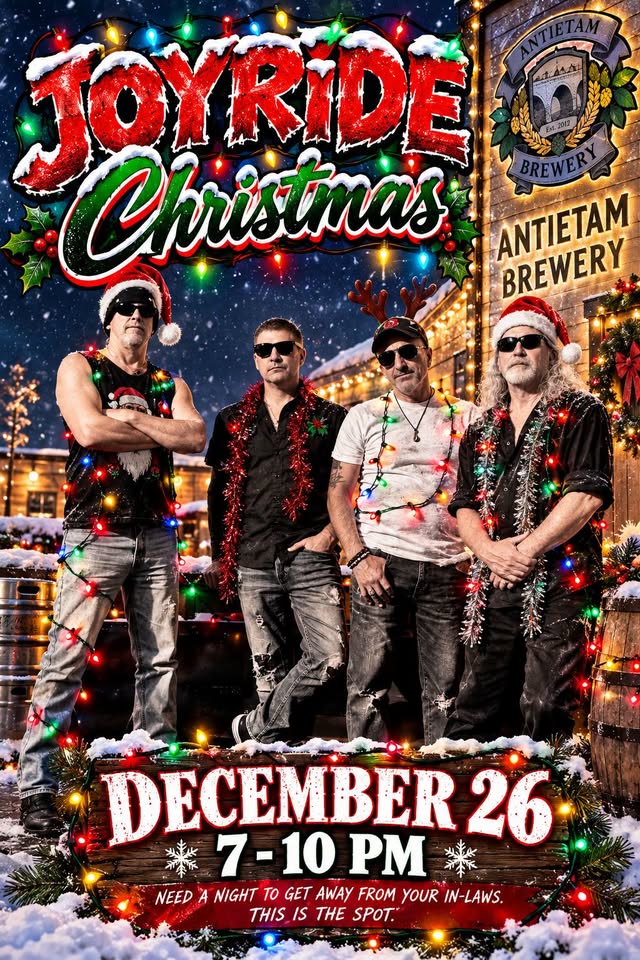 Joyride band photo: four band members in Santa hats and sunglasses wrapped in Christmas lights, posed in front of a snowy, lit-up building
